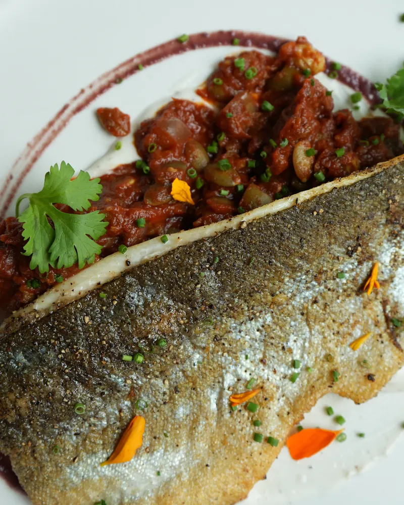 Crispy-skin fish fillet with tomato relish, cilantro and edible flowers