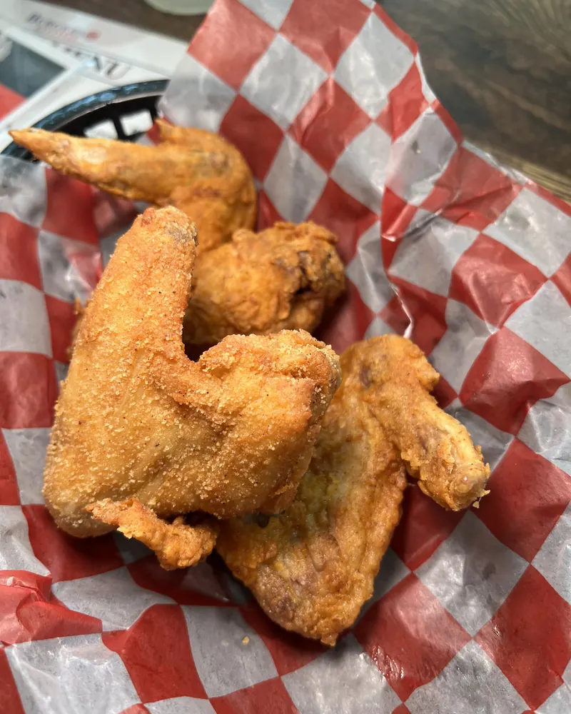 Fried chicken wings in a basket lined with red checkered paper