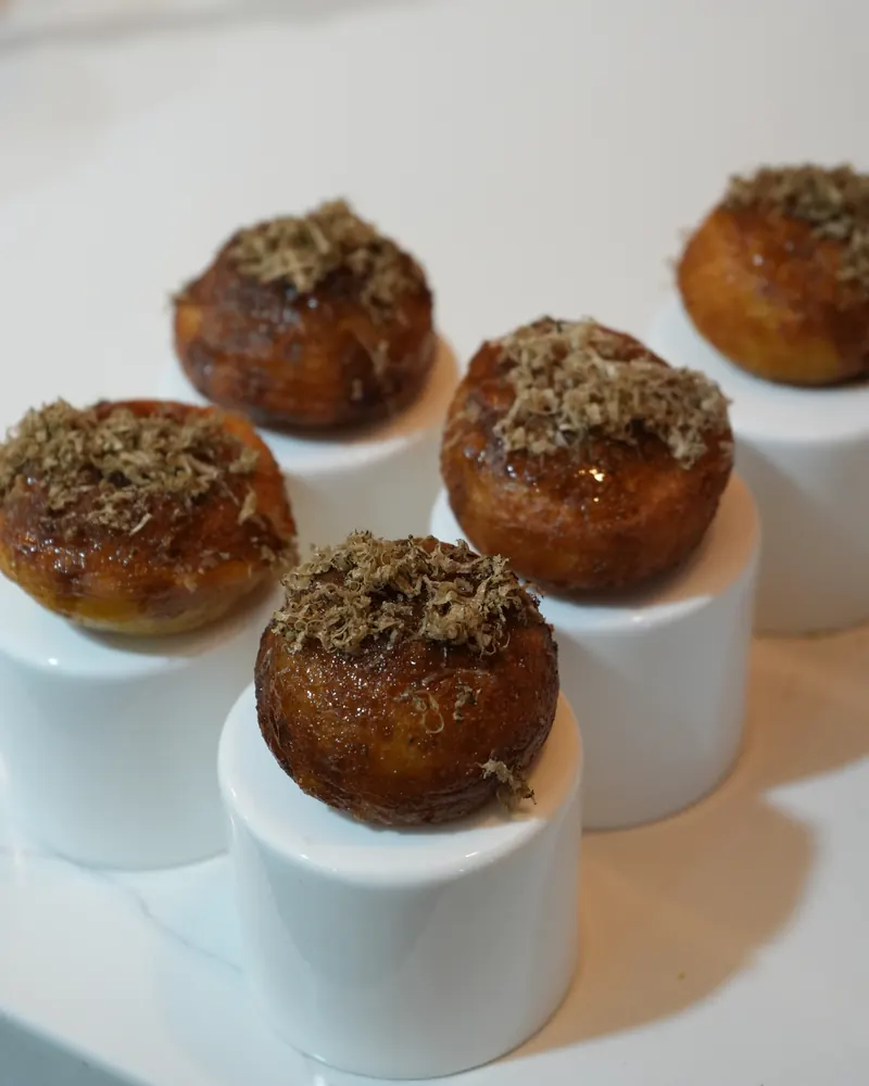 Glazed pastries topped with fine shavings, served on white pedestals
