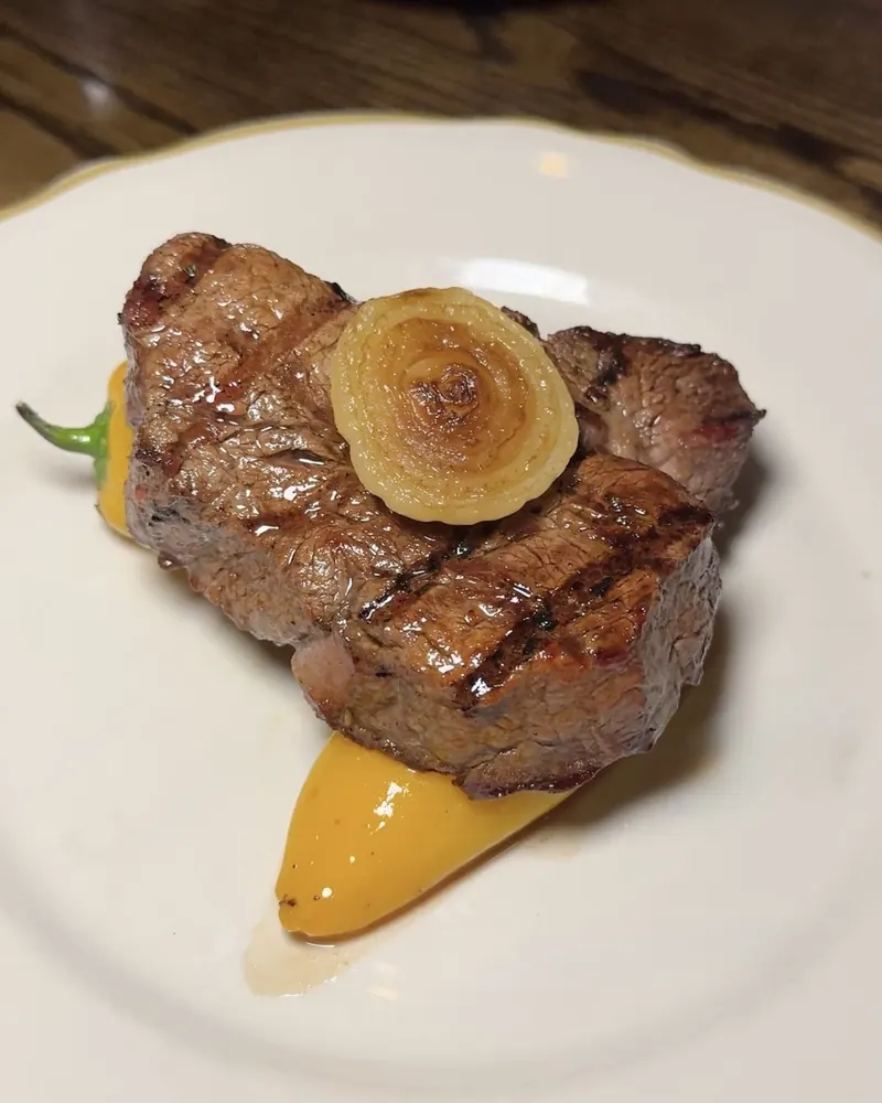 Grilled steak topped with a roasted onion, served with a sweet pepper