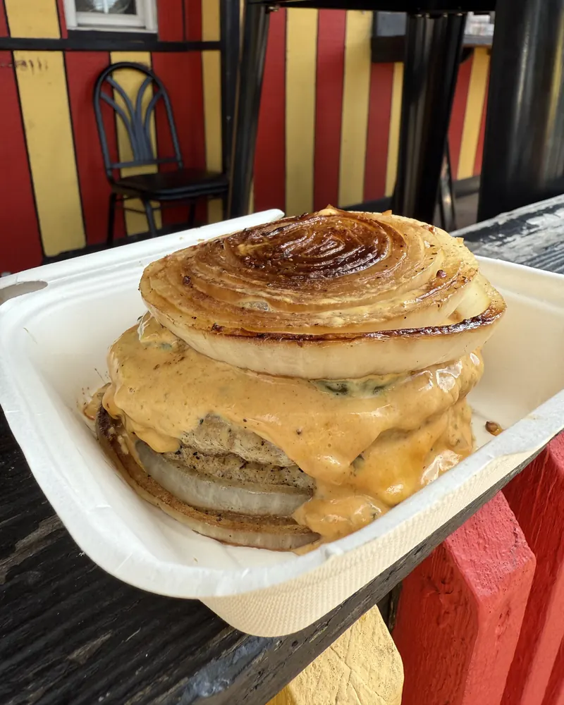 Burger between charred onion slices with melted cheese sauce