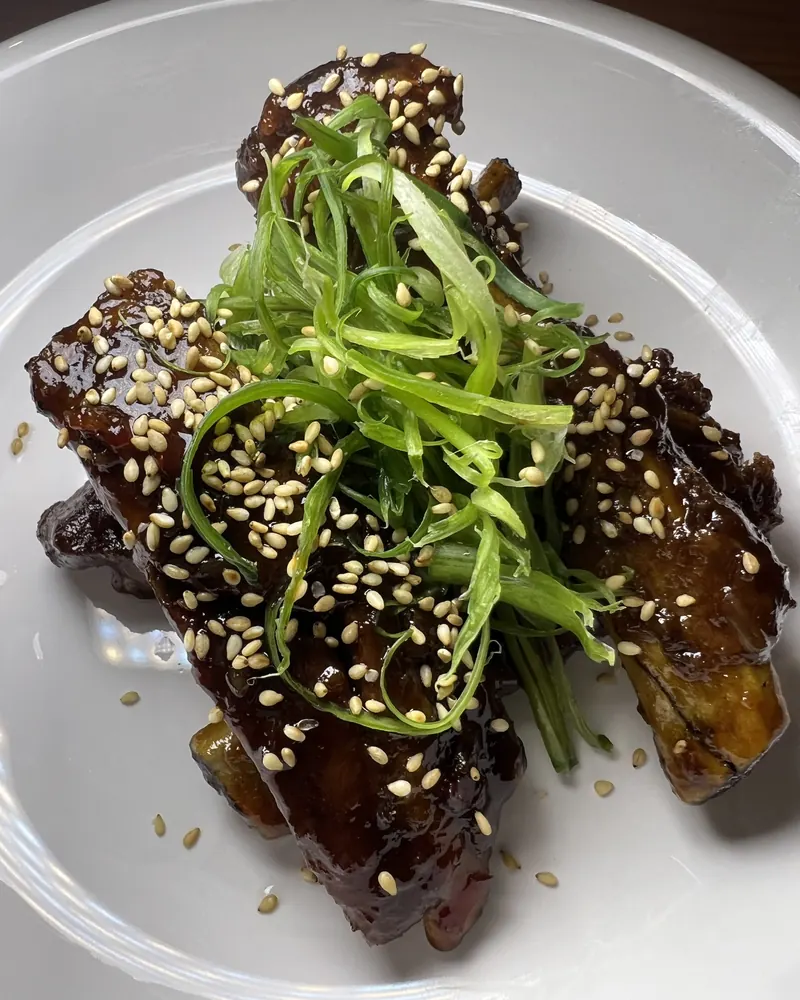 Sticky glazed dish topped with sesame seeds and shredded scallions